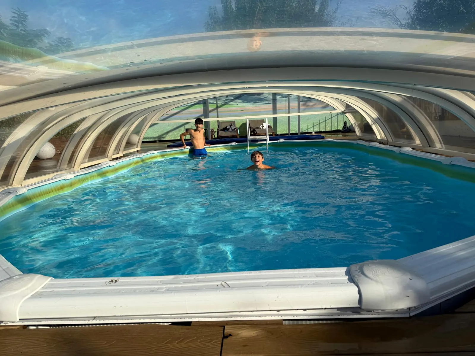 Children in the heated outdoor pool at Villa Patty Assisi, under the transparent sliding panoramic cover.